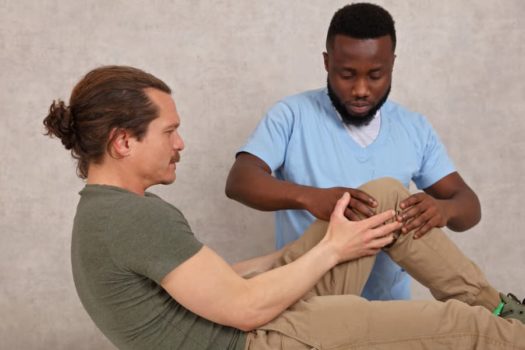 Physical therapist assistant helps patient perform exercises for knee