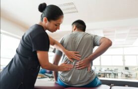 A clinical massage therapist examines a client’s back 