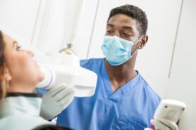 Dental assistant doing X-ray on patient’s teeth