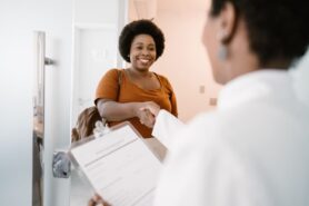 Healthcare worker greets smiling patient in medical office