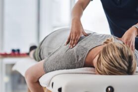Massage therapist presses on back of client