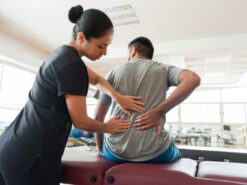 Clinical massage therapist inspecting lower back of client experiencing chronic pain 