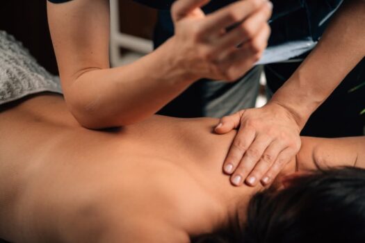 Massage therapist using elbow to perform neuromuscular massage on client’s back