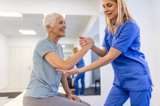 Physical therapy assistant aiding patient with exercises for osteoporosis treatment
