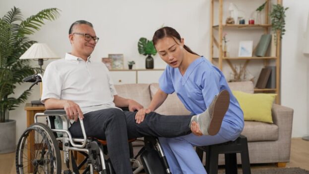 Physical therapy assistant helping patient in wheelchair with leg stretching