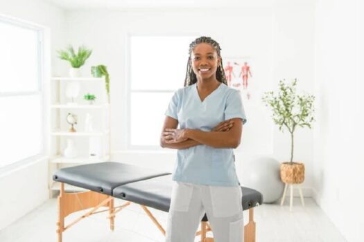 Smiling massage therapist standing near massage table